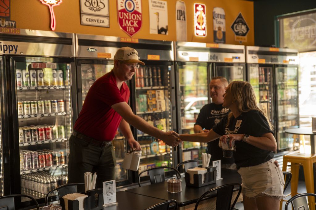 A guest pouring drinks by the to-go coolers at Beer Me!